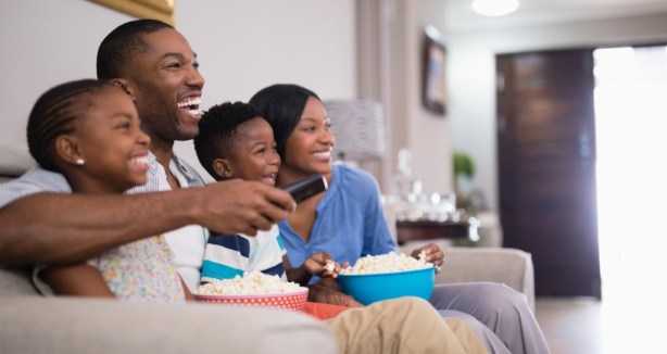 Веселая семья с попкорном во время просмотра телевизора у себя дома